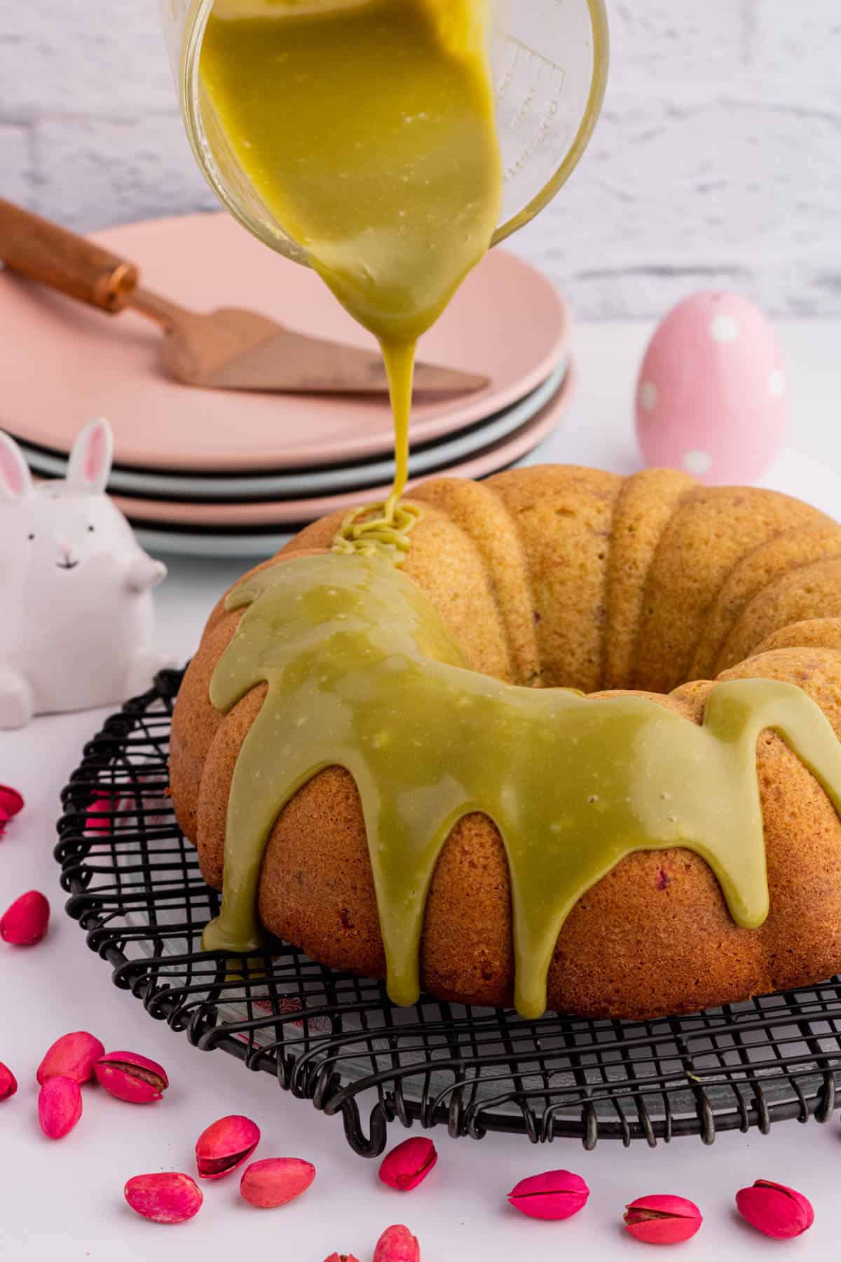 Green glaze being poured over a golden baked bundt cake .