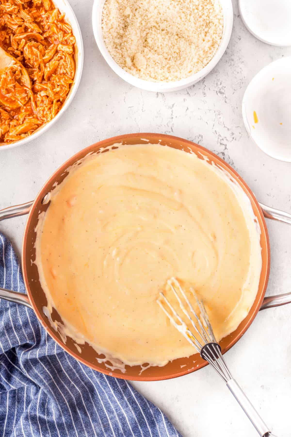 Overhead of cheese sauce in a pan with a whisk