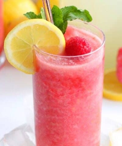 Chambord Frozen Lemonade in a tall glass with lemon, raspberry and mint garnish