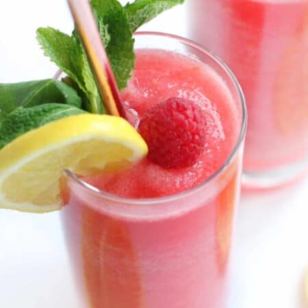 Chambord Frozen Lemonade in a tall glass with lemon, raspberry and mint garnish