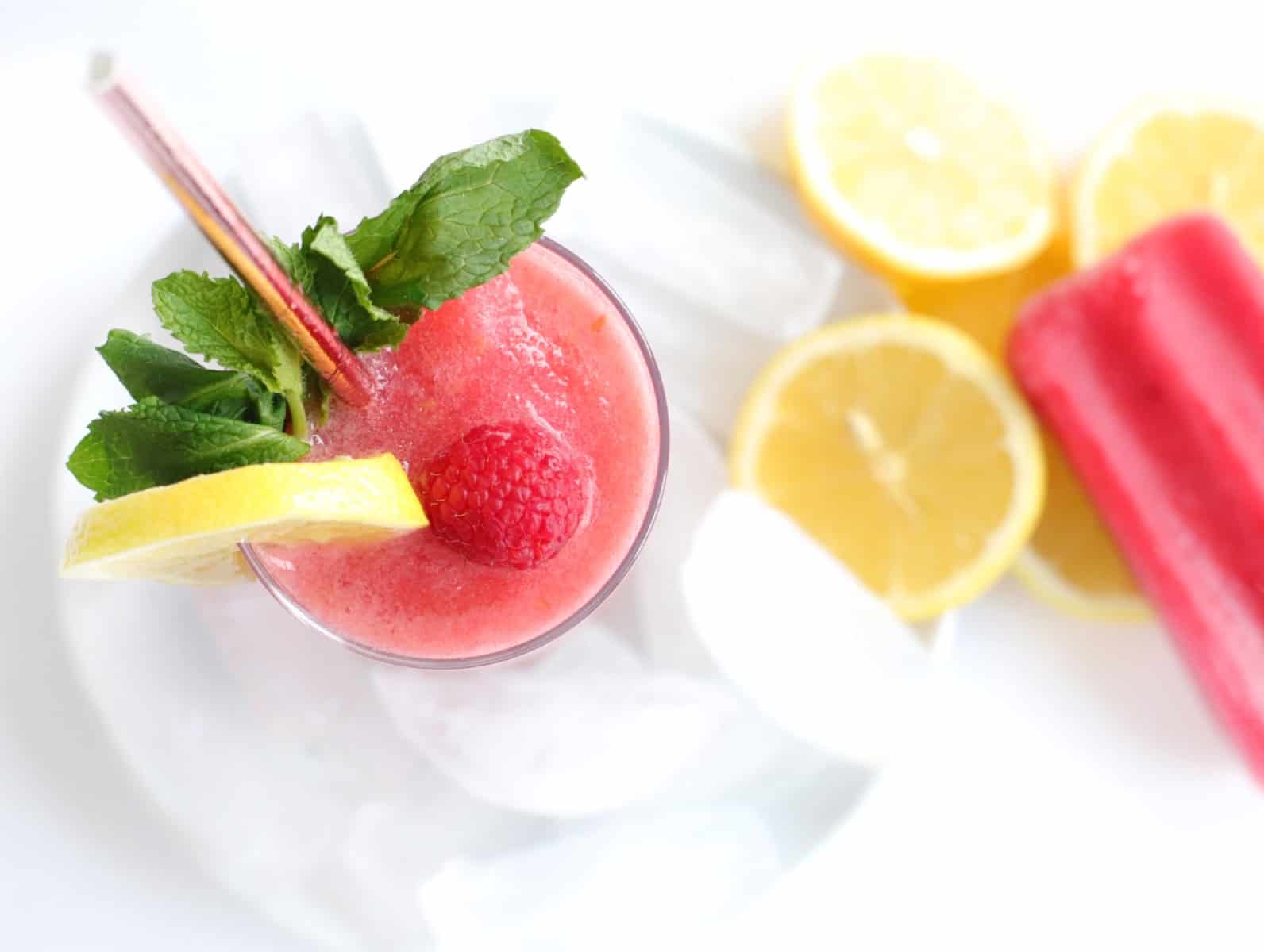 Overhead shot of a frozen lemonade garnished with lemon slice, mint and a raspeberry
