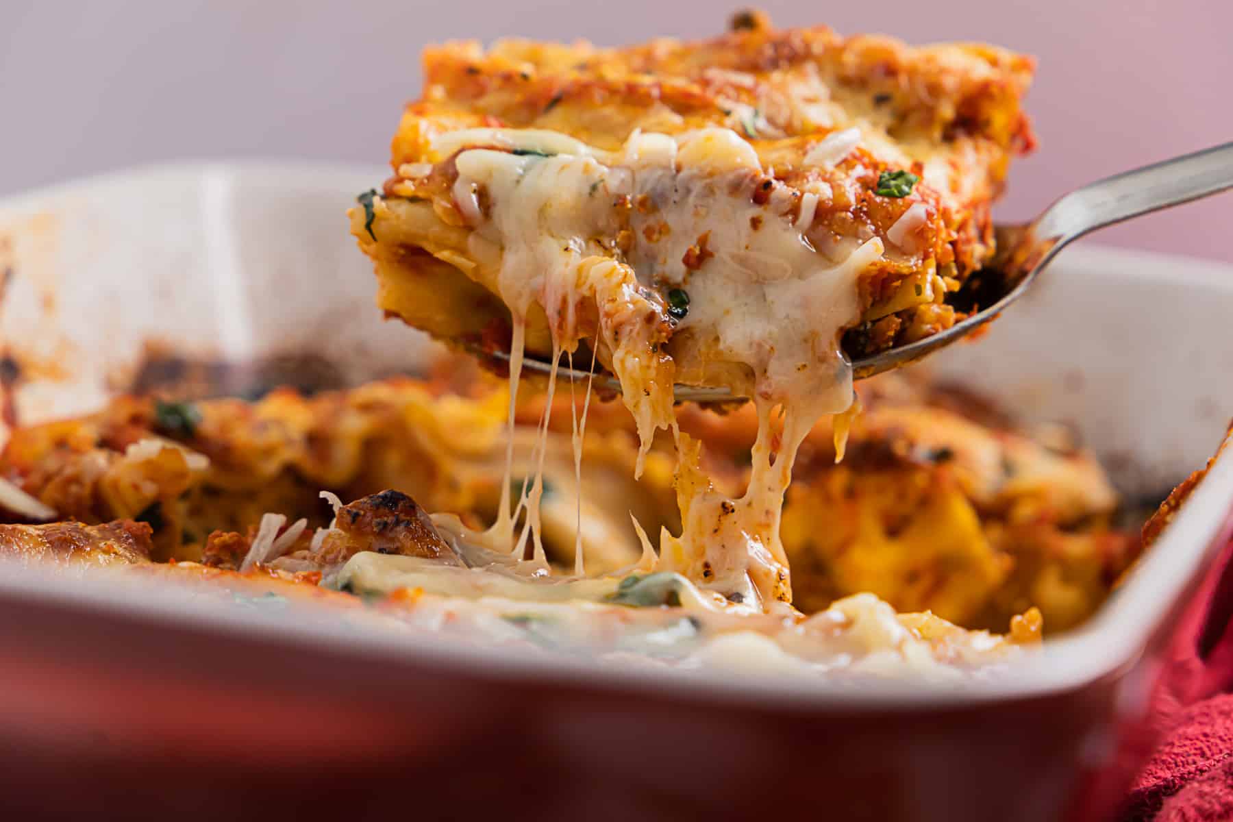 Side view of a cheese pull with cheese manicotti on a serving spoon. 