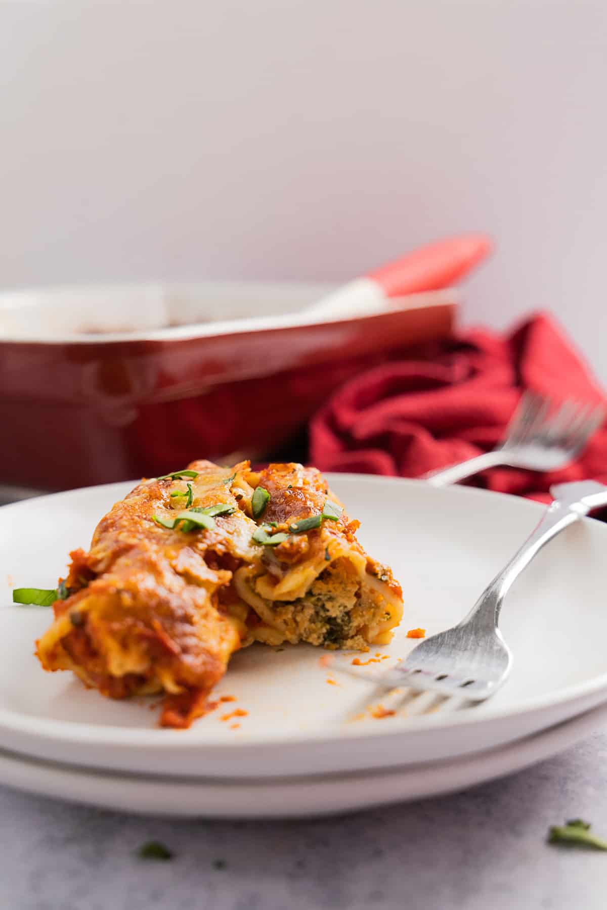 Side view of the inside of a manicotti stuffed with ricotta and spinach, a fork on the side. 