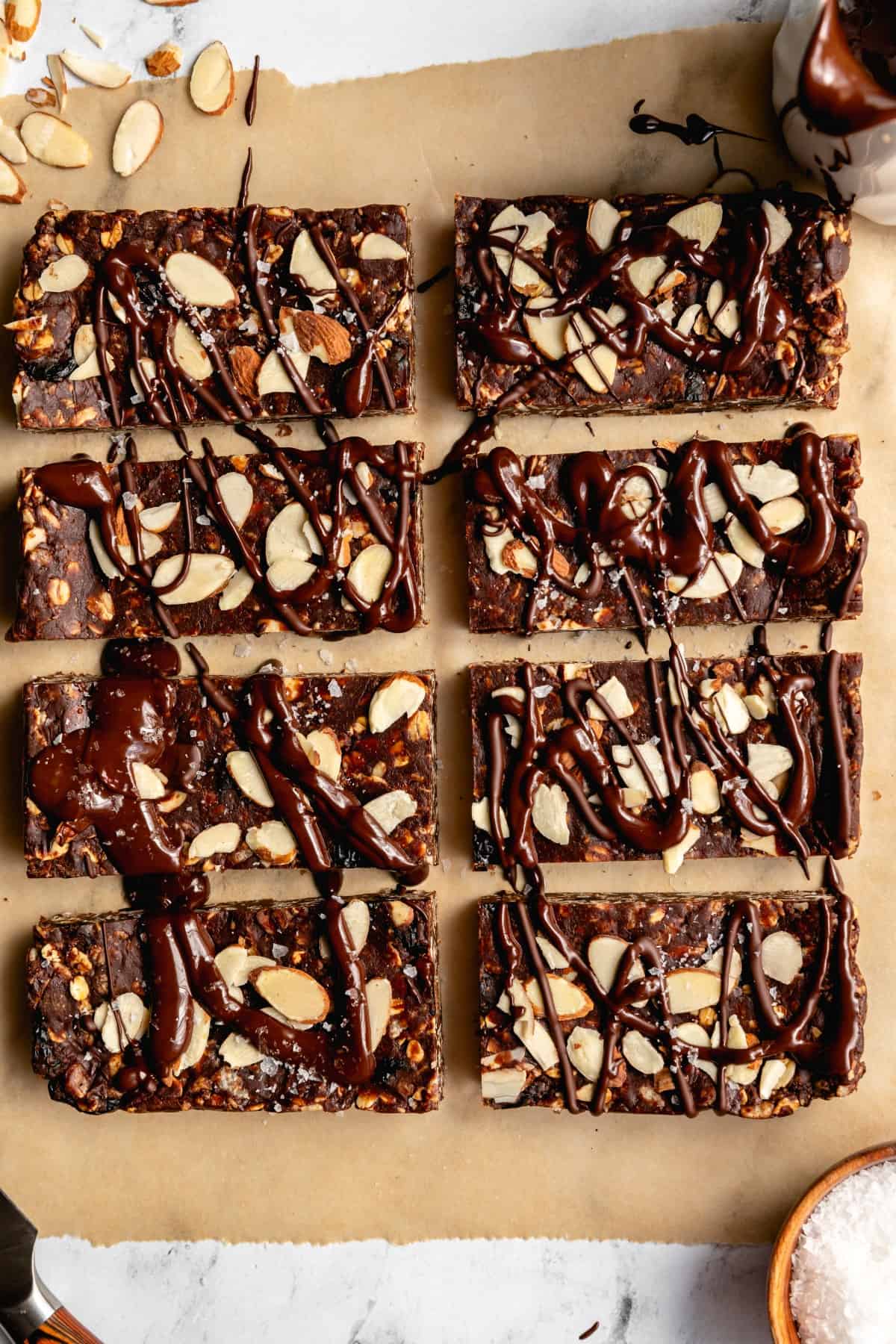 Chocolate drizzled on Chocolate Cherry Granola Bars on parchment. 