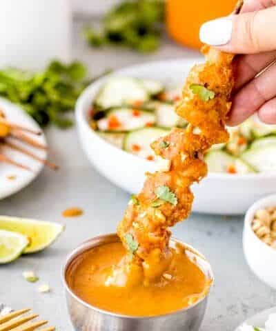 Dipping a chicken satay into sauce