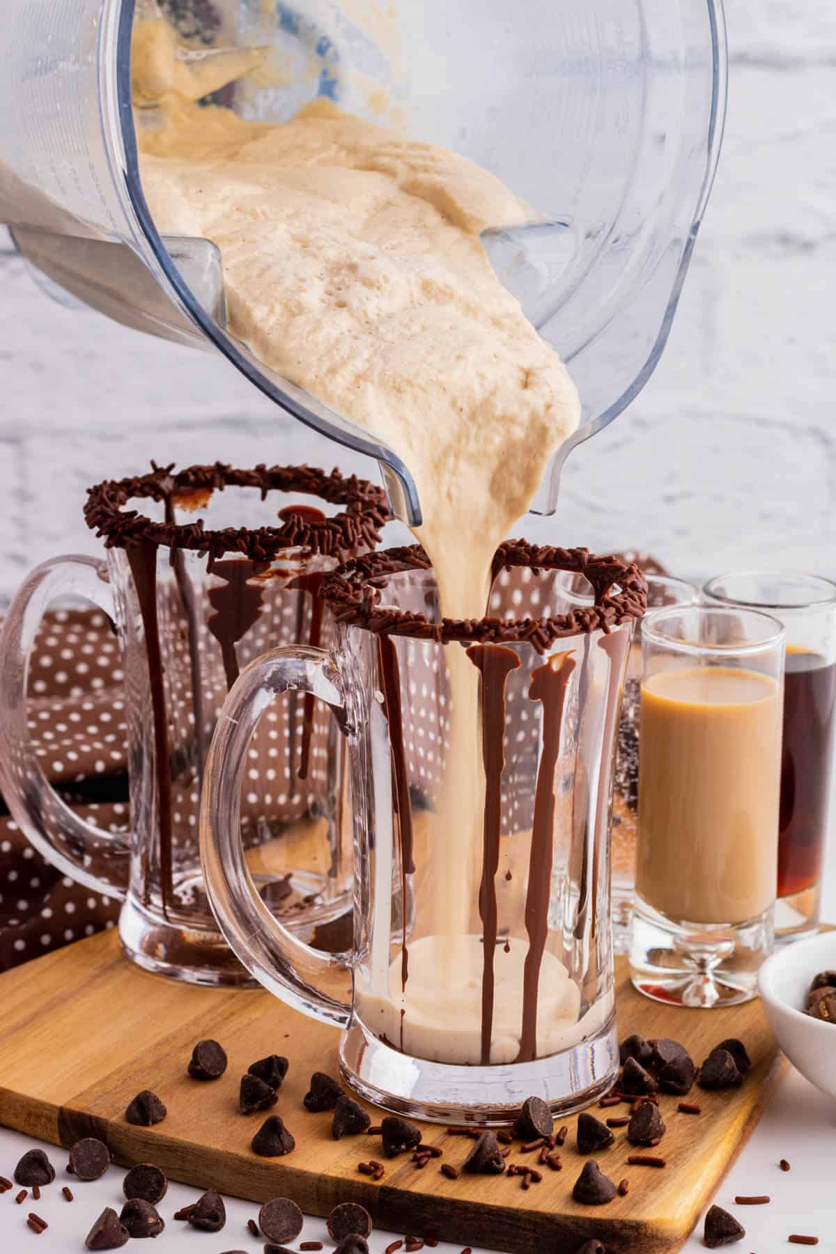 Chocolate mudslide being poured into a glass mug decorated with chocolate sauce.