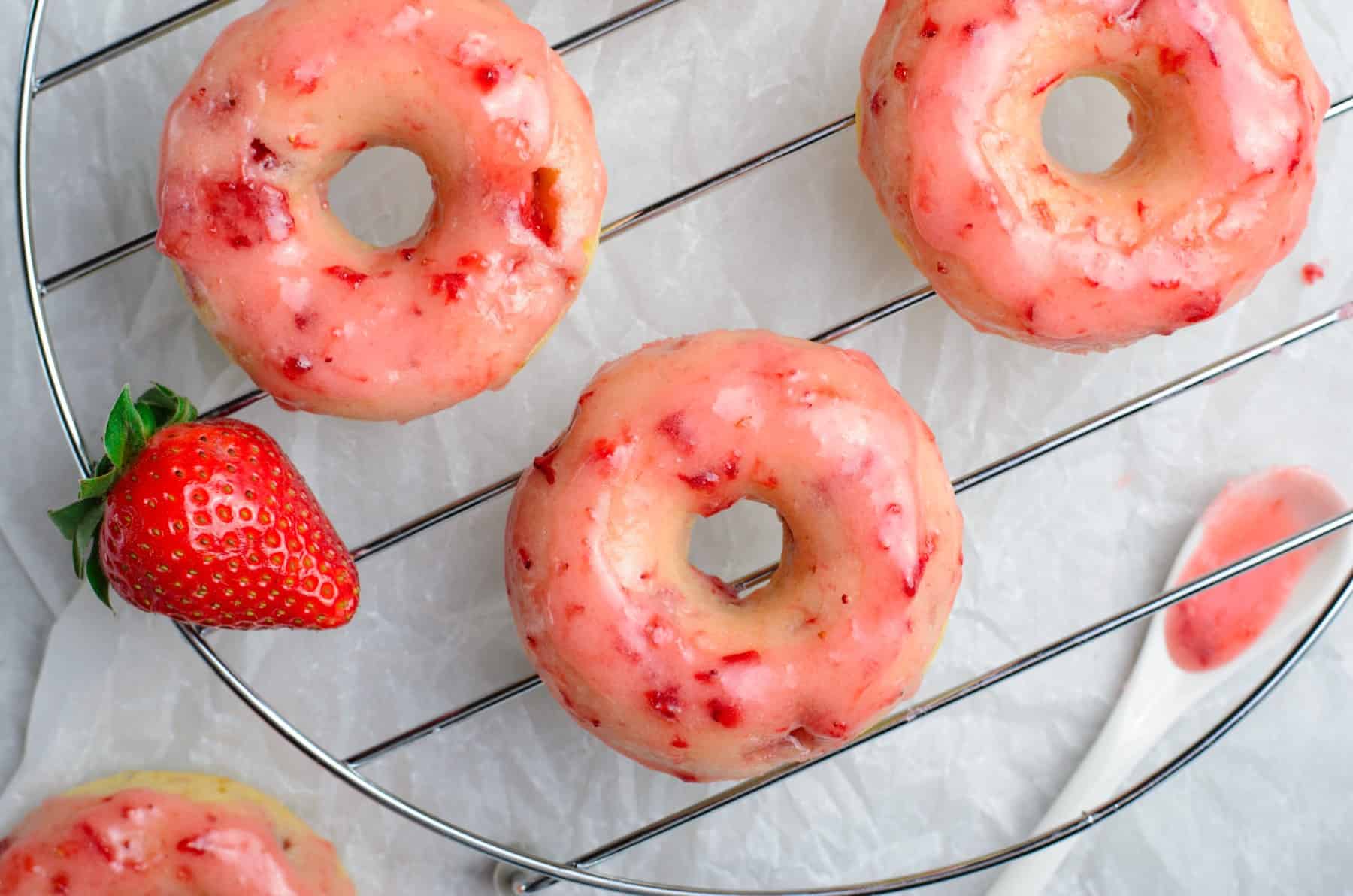 Overhead shot of strawberry donuts on a cooling rack