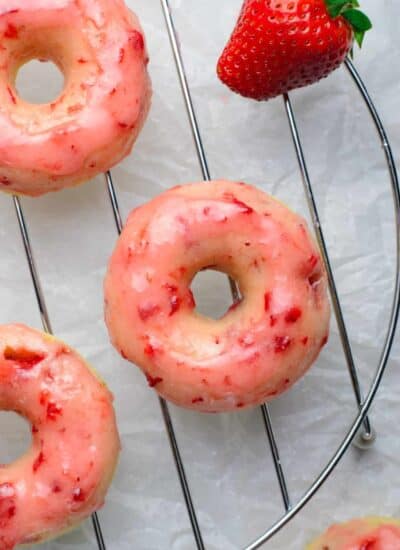 Overhead of strawberry donuts on a rack.