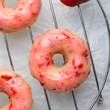 Overhead of strawberry donuts on a rack.