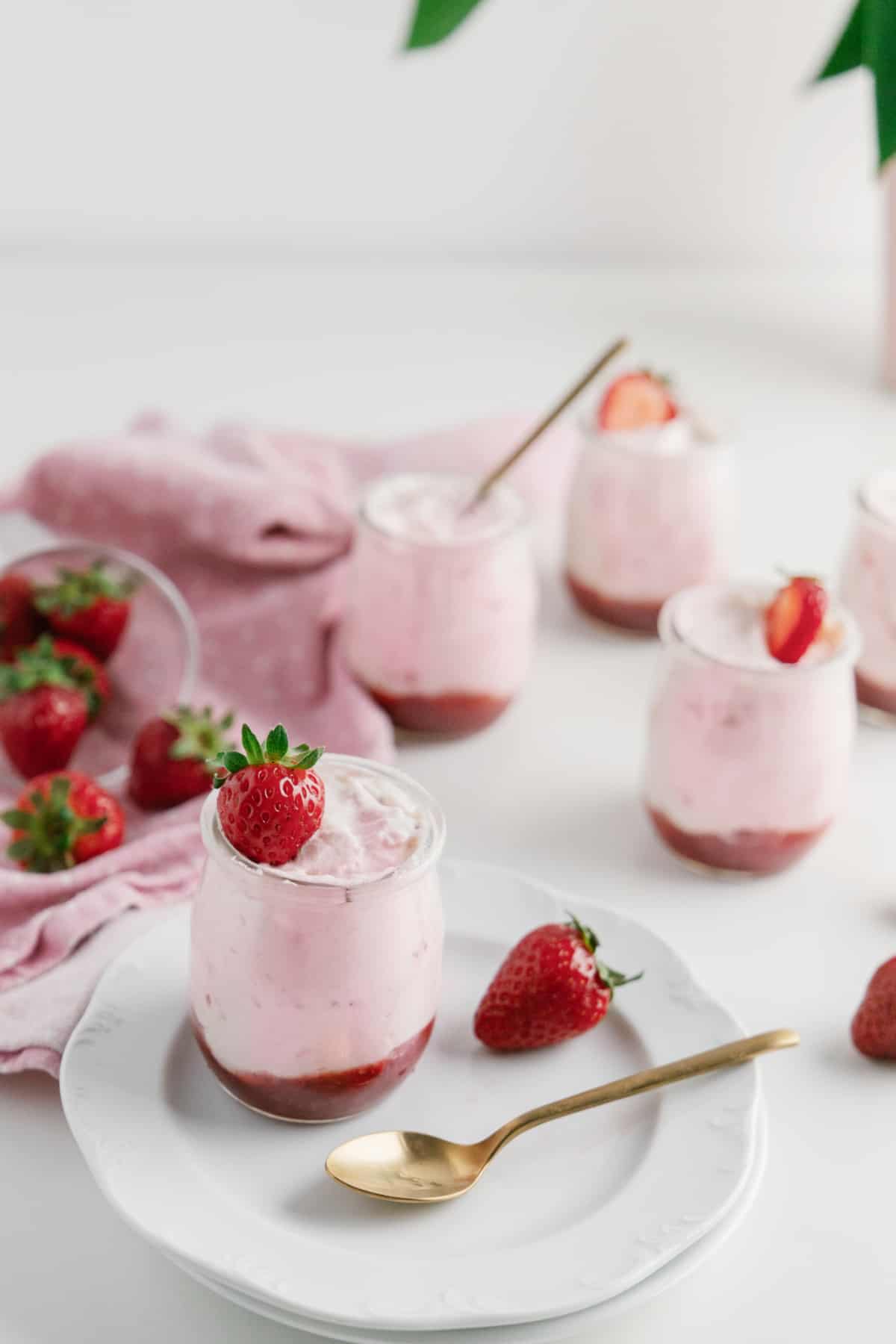 Scattered jars of strawberry mousse and strawberries. 