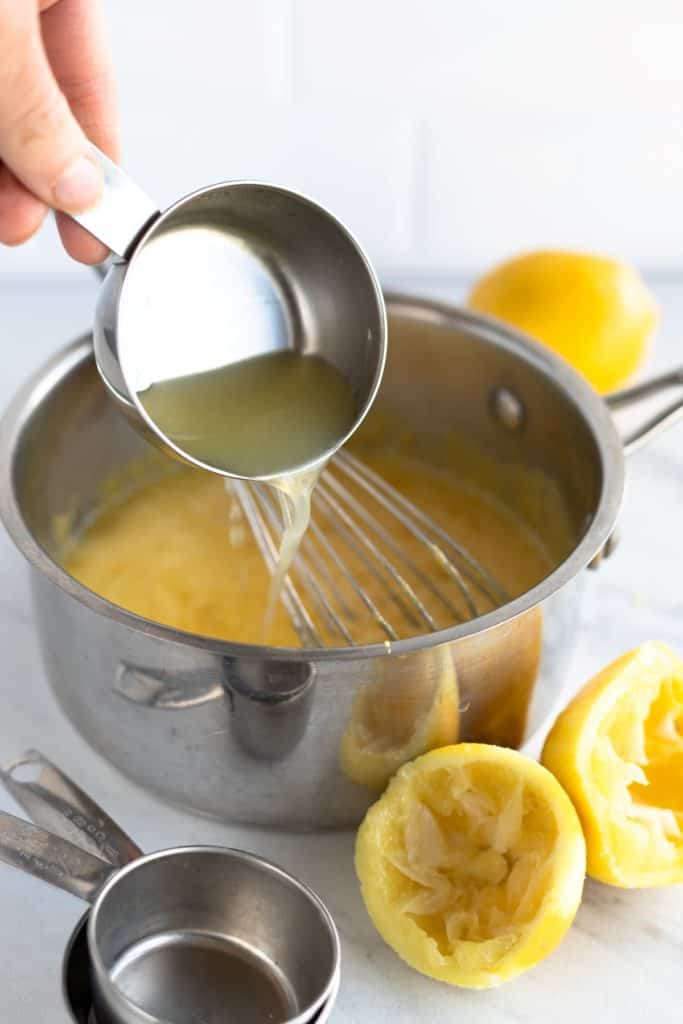 Adding lemon juice to eggs in a pot