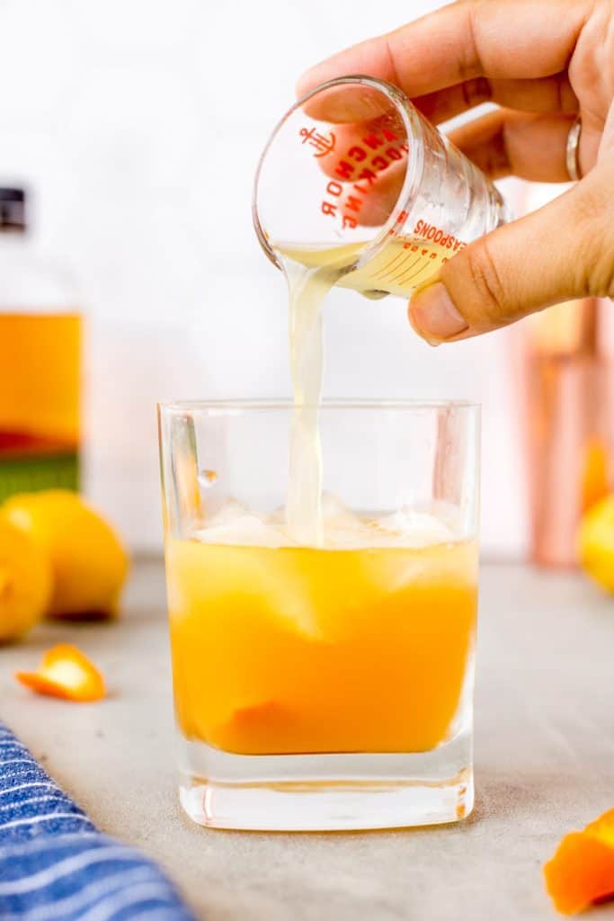 Pouring lemon juice into a whiskey sour