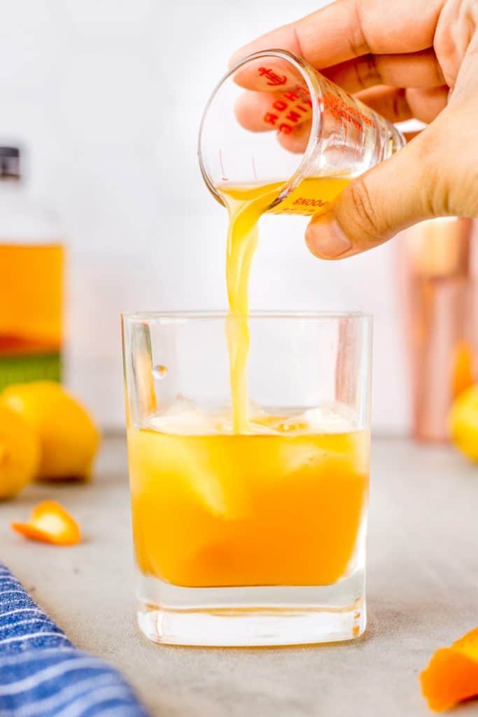 Pouring orange juice into a glass with whiskey