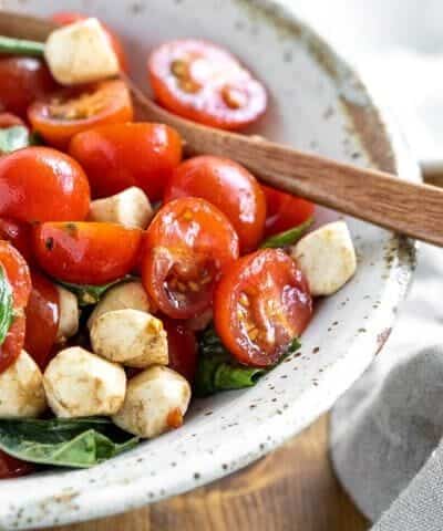 Bowl of caprese salad with a wooden spoon