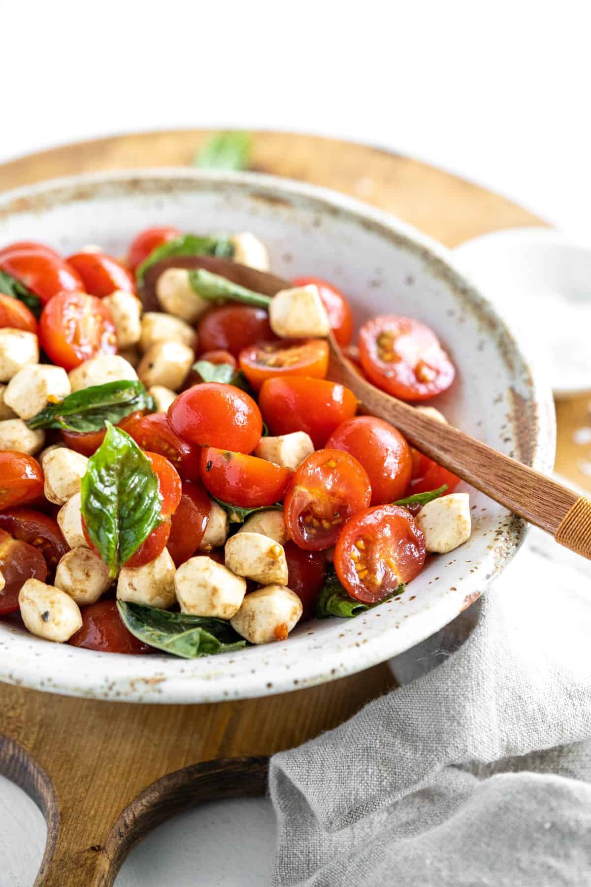 Caprese salad in a bowl with a wooden spoon