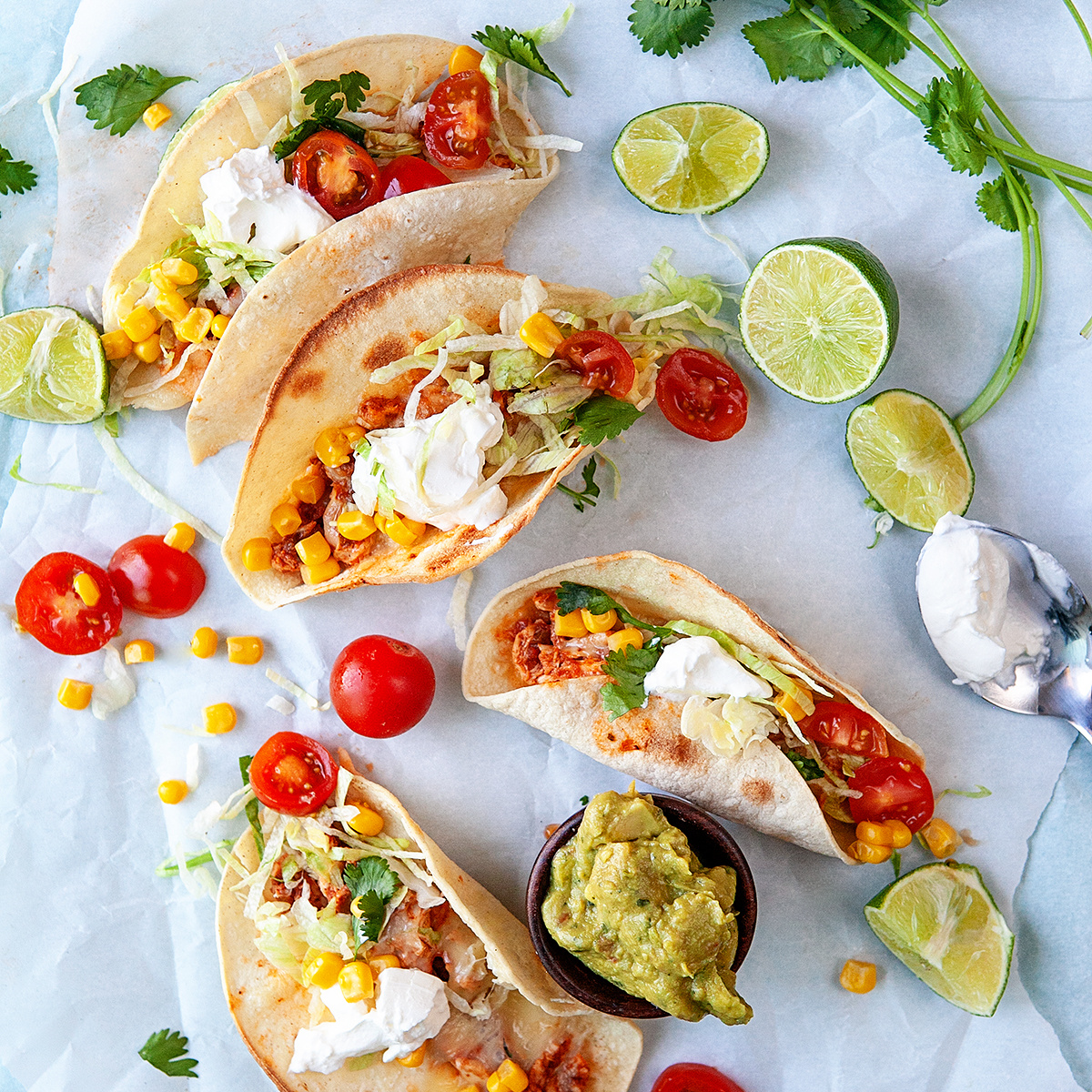 Overhead shot of tacos and toppings on parchment paper