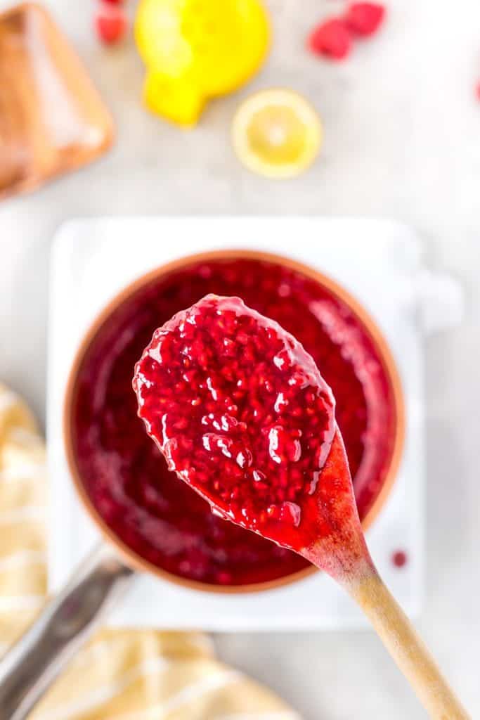 Holding up a wooden spoon with raspberry sauce