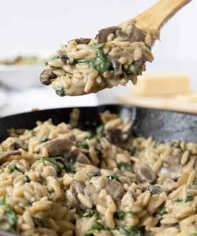 Taking a spoonful of mushroom orzo from the pan
