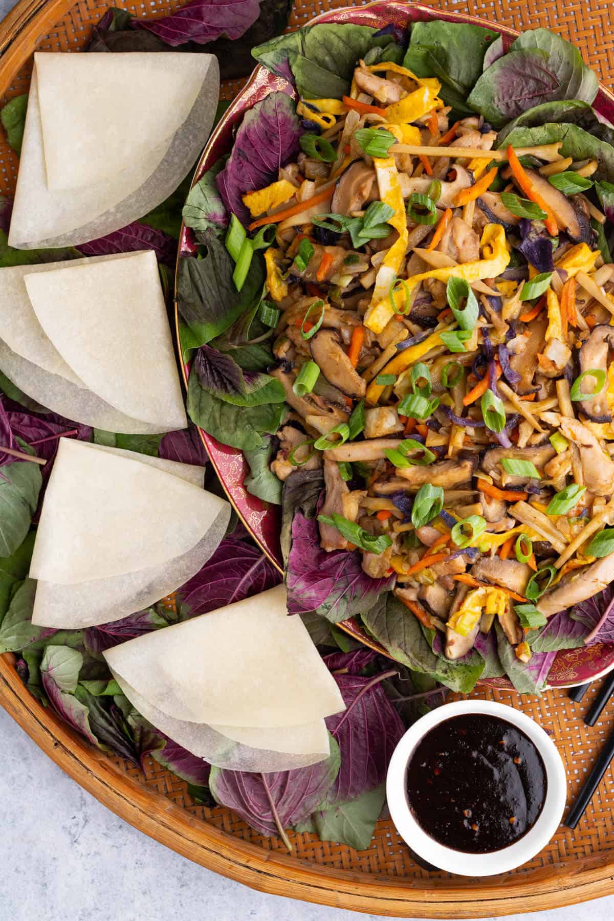 A platter full of colourful Moo Shu Chicken with Chinese pancakes and a dish of hoisin sauce.