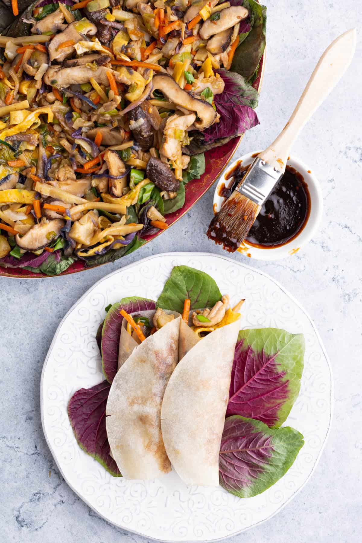 A platter full of colourful Moo Shu Chicken and two filled and rolled pancakes.