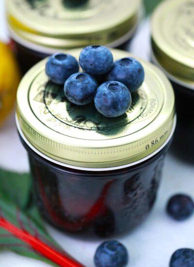 Blueberries on top of a small jar of jam.