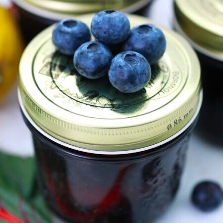Blueberries on top of a small jar of jam.