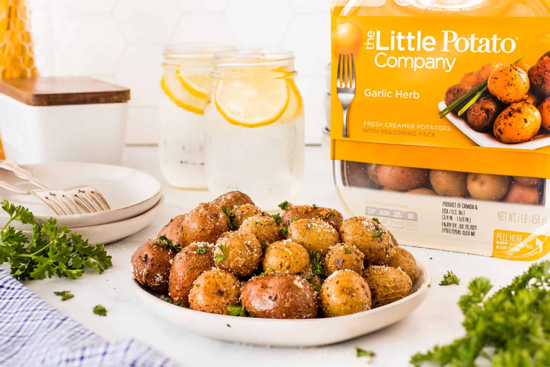 Potatoes on a plate with a package of potatoes behind from Little Potato Company. 