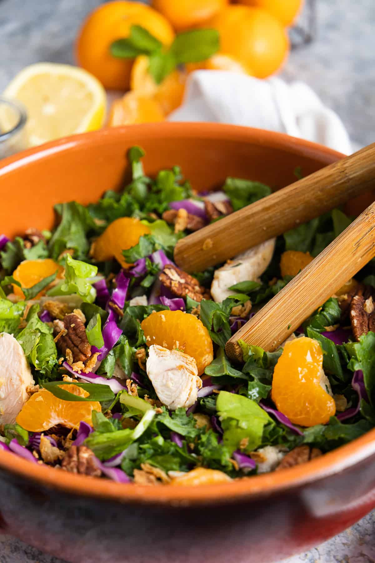 Close up of the mandarin chicken salad with wooden tongs.