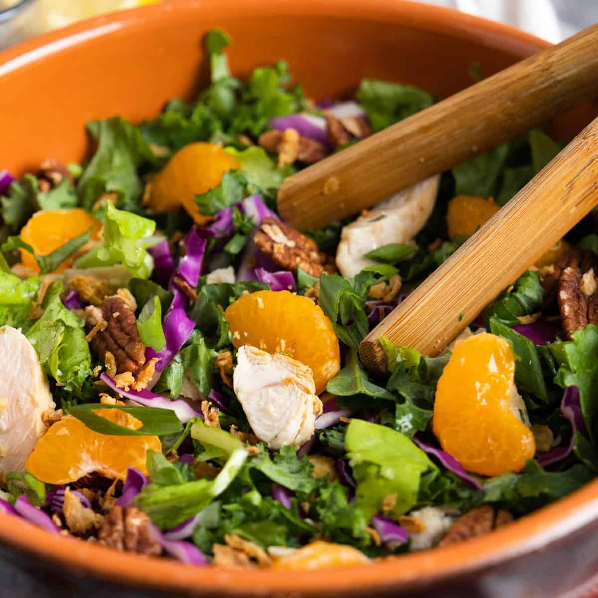 Mandarin Chicken Salad in a wooden bowl with tongs. 