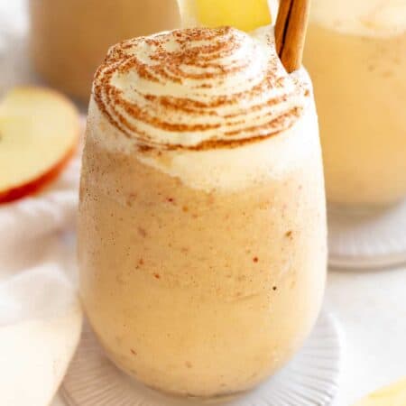 Apple Pie Smoothie in a glass with whipped cream and a cinnamon stick