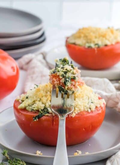 Artichoke Stuffed Tomatoes with a forkful resting on a tomate