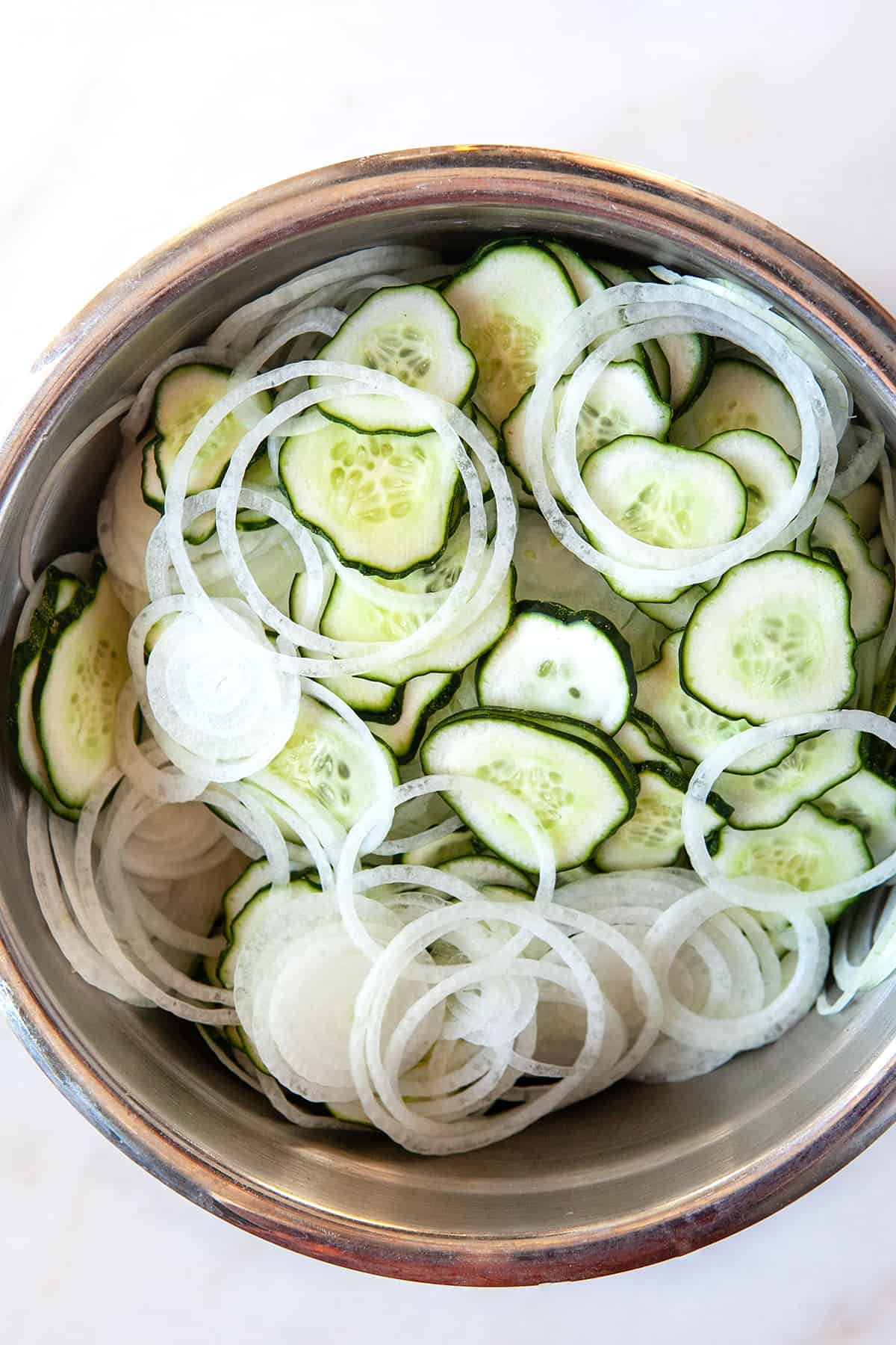 Overhead of sliced cucumbers and onions in a bowl. 