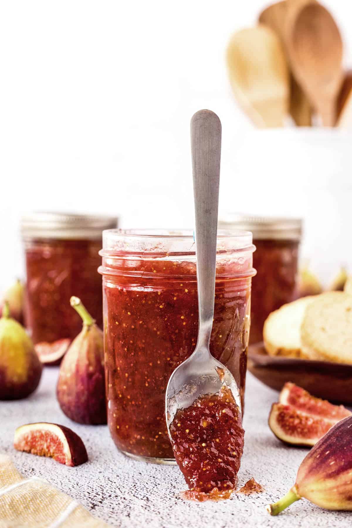 Spoonful of fig jam leaning up against a jar of fig jam