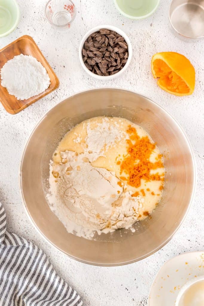 Flour and orange zest being adding to a bowl