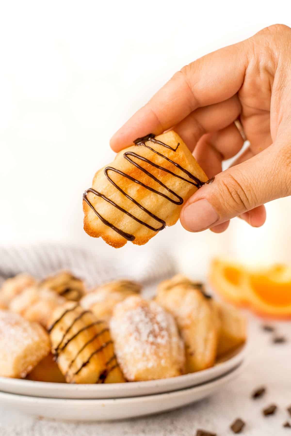 Holding an Orange Madeleine Cookie that was just drizzled with chocolate.