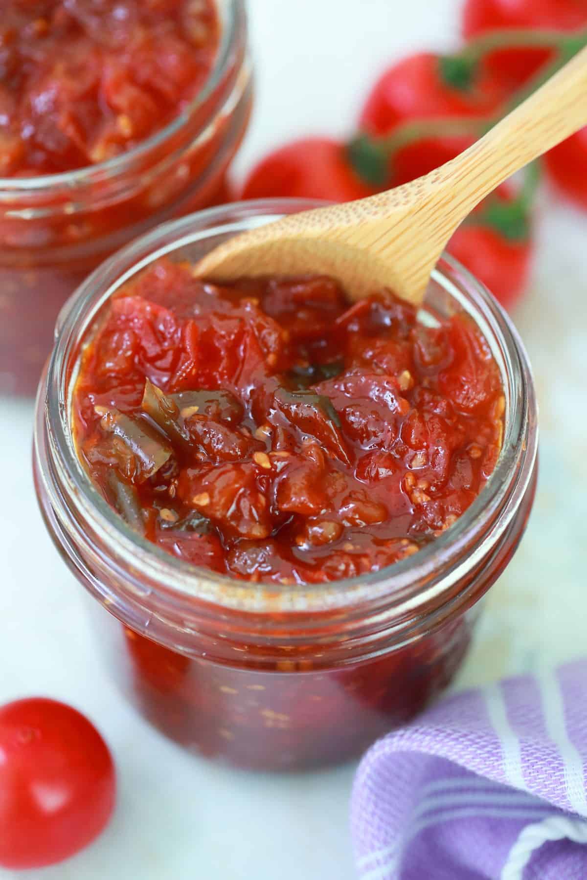 Jar of tomato jam with a wooden spoon. 