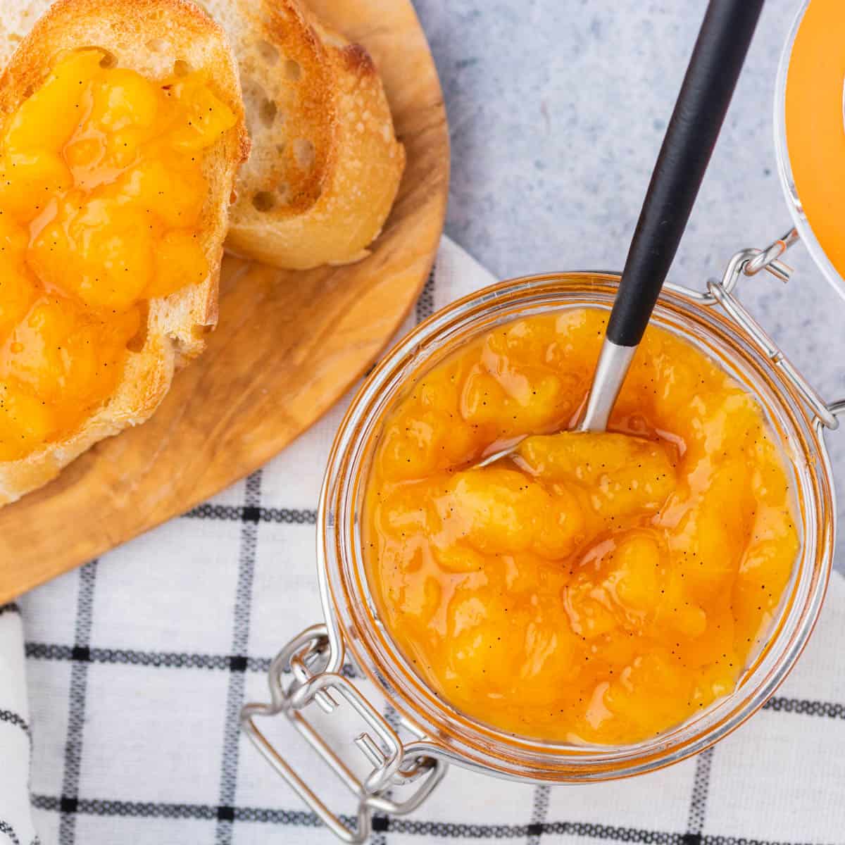 A spoon in a jar of Peach Freezer Jam.