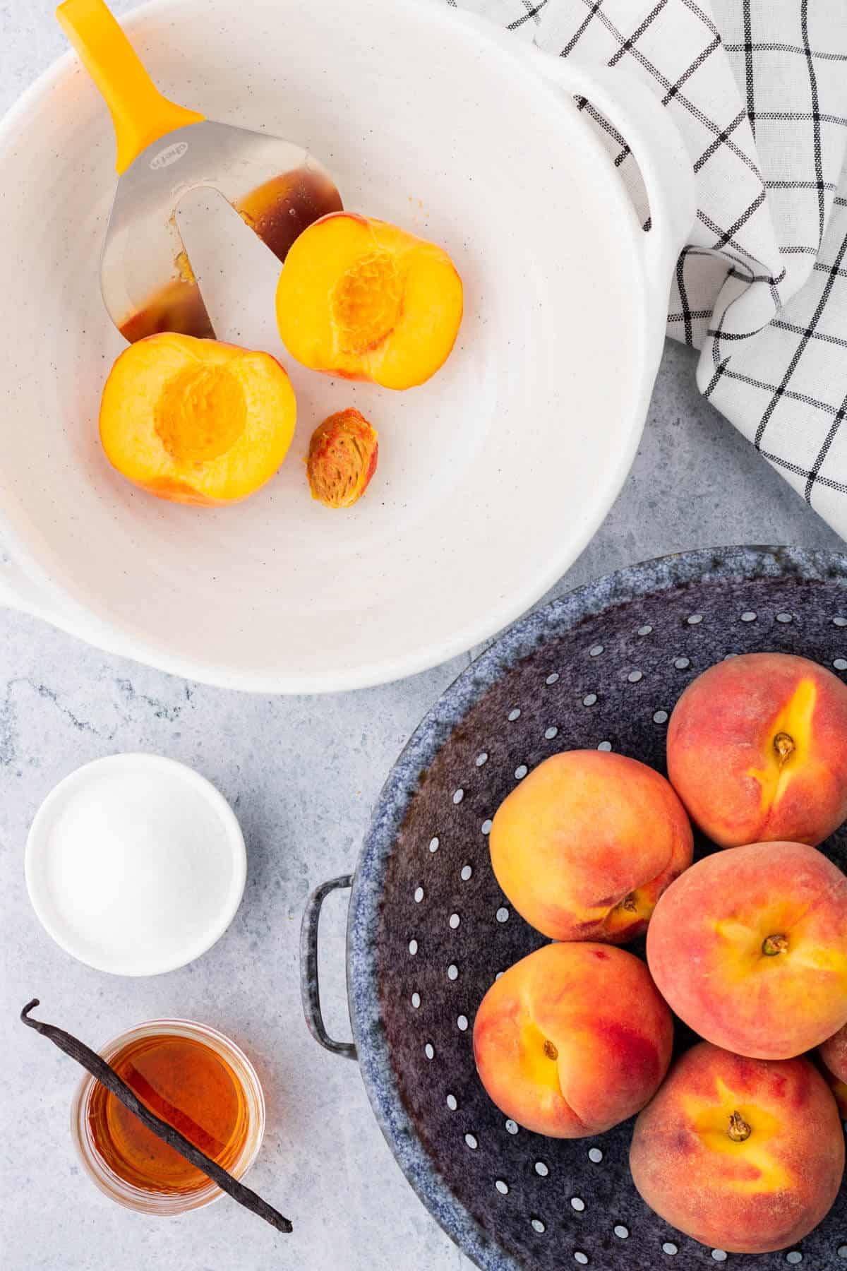 A split peach in a white bowl with a peach splitter tool.