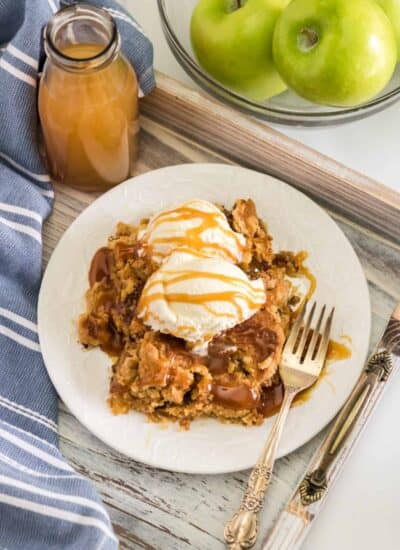 Apple Dump Cake on a plate with ice cream and caramel sauce.
