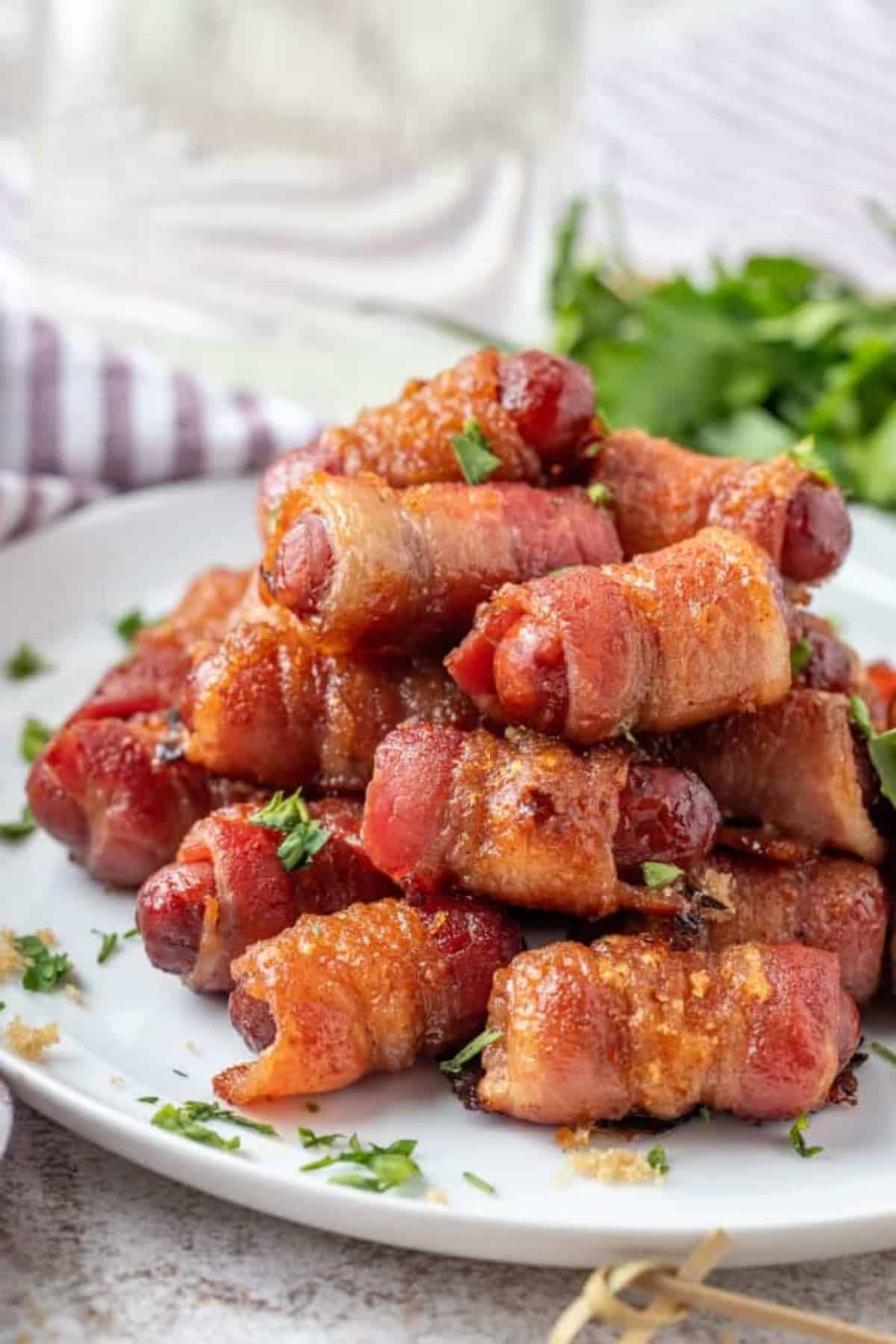 Brown Sugar Bacon Wrapped Smokies piled on a white plate
