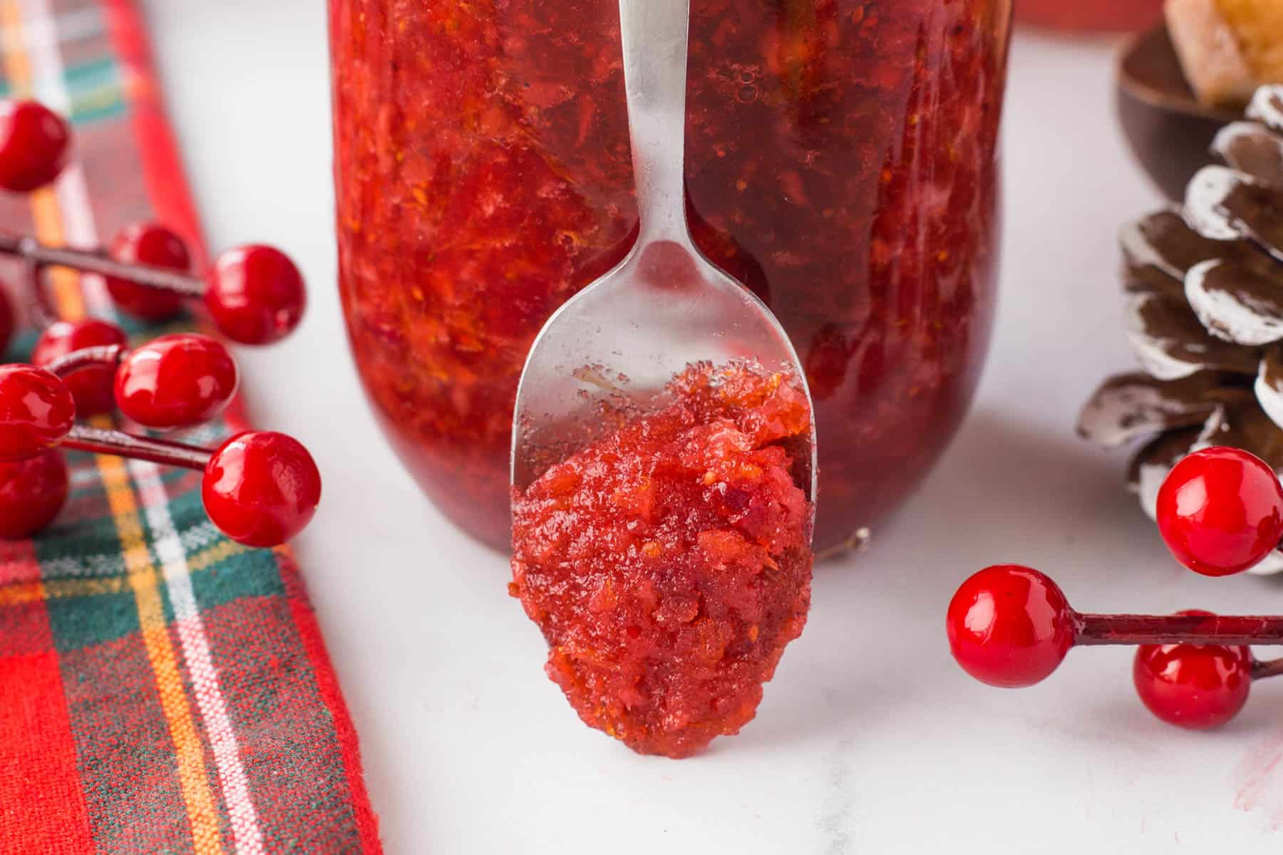 Horizontal photo showing jam on a spoon leaning on a jar