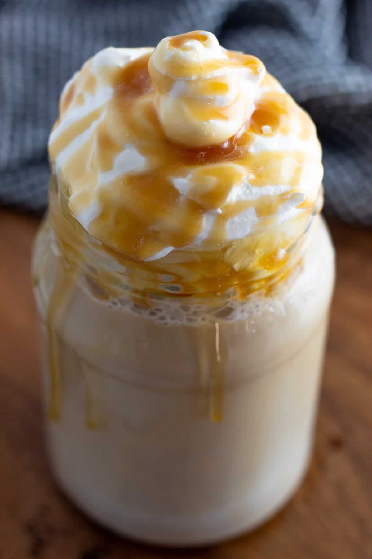 Close-up of whipped cream and caramel sauce on top of a caramel macchiato. 