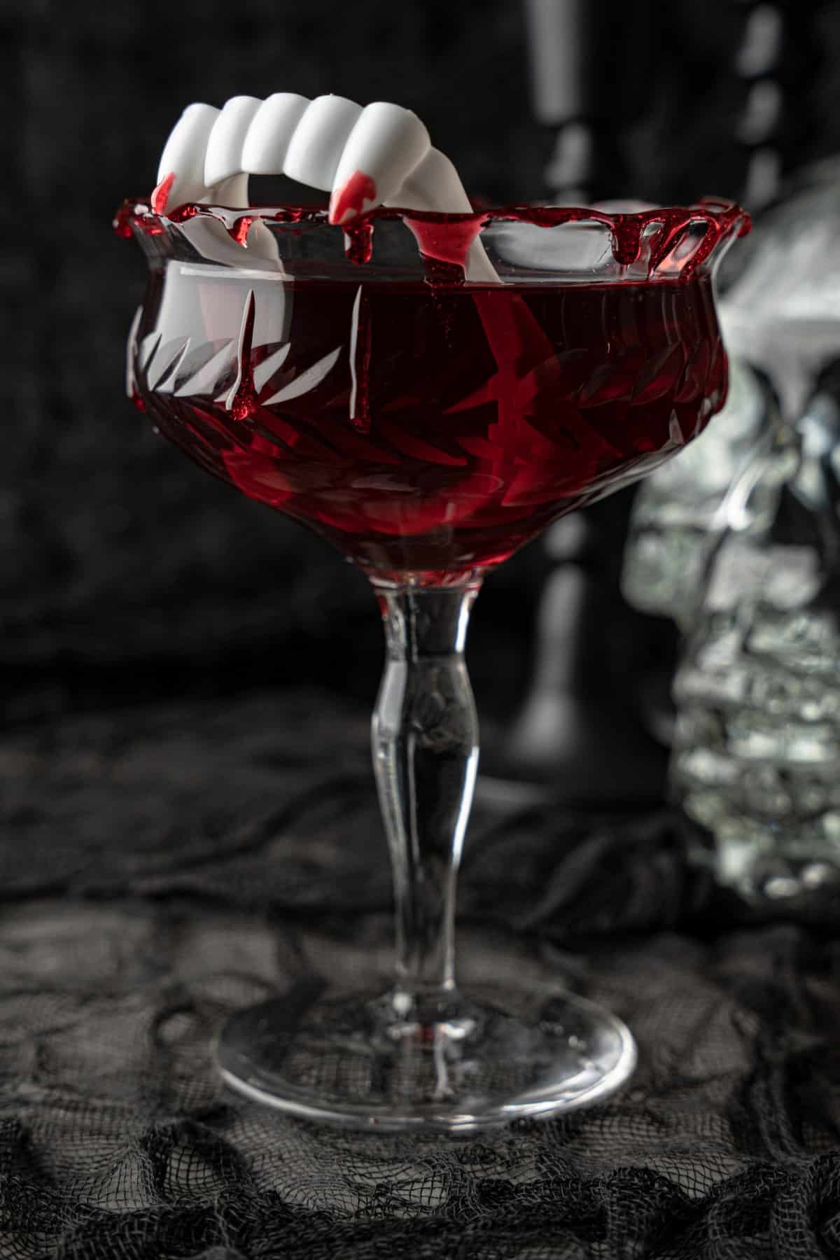 Close-up of blood dripping down a glass with vampire teeth in a Dracula's Kiss Cocktail
