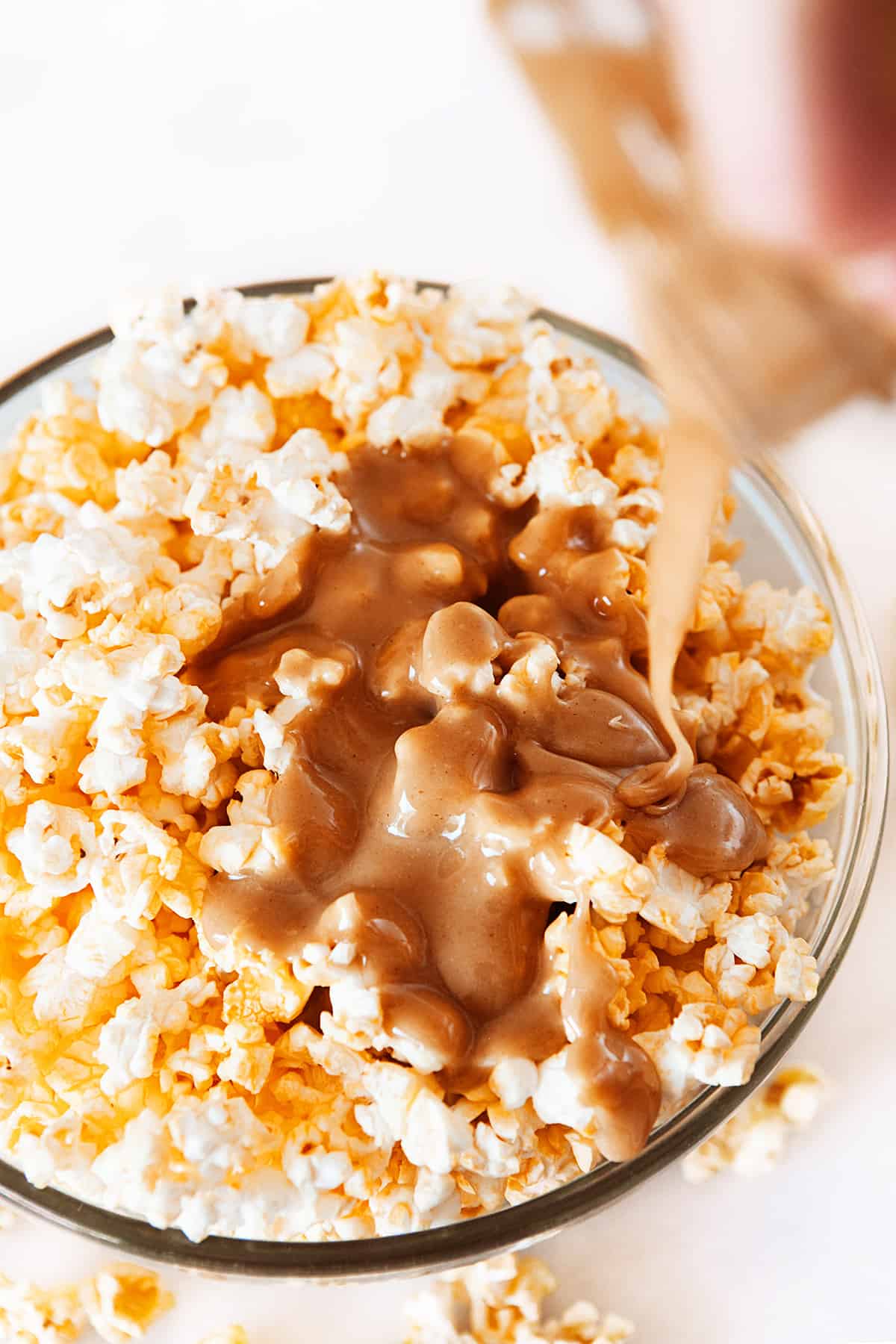 Overhead  pouring peanut butter sauce on popcorn 