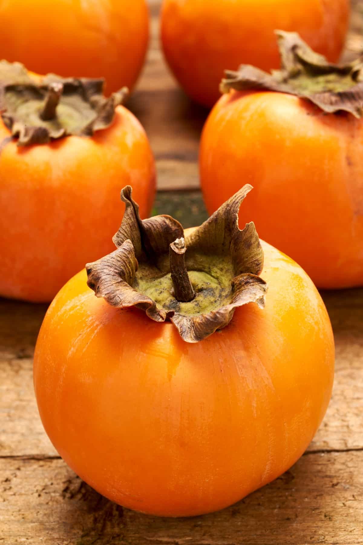 Fresh and sweet persimmons propped up on an old wooden table