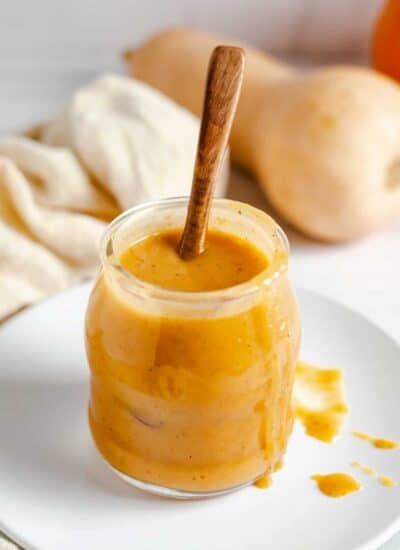 Pumpkin caramel sauce in a jar with a wooden spoon in it.