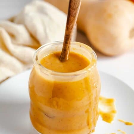 Pumpkin caramel sauce in a jar with a wooden spoon in it.