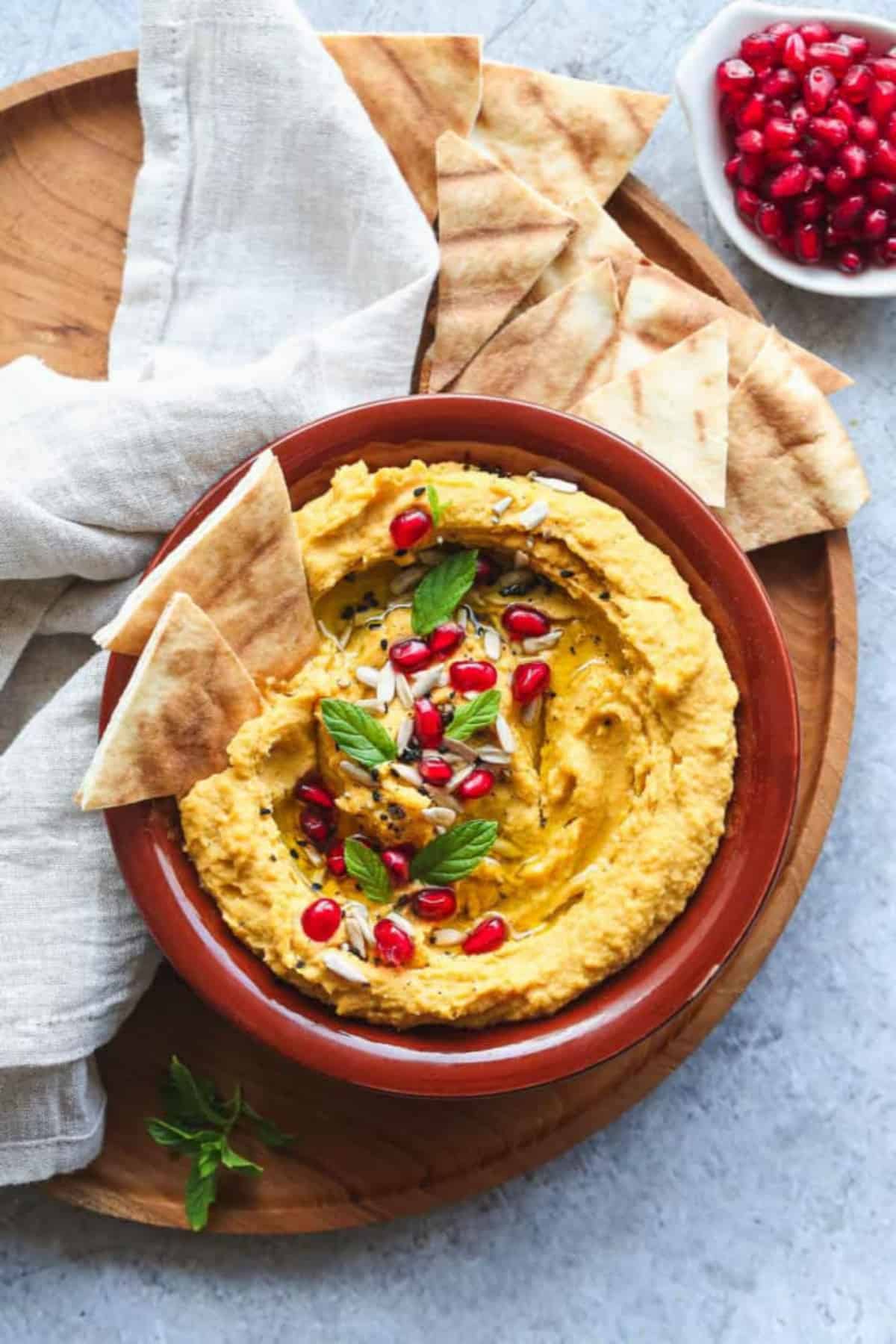 Roasted sweet potato hummus in a terracotta bowl with pita chips