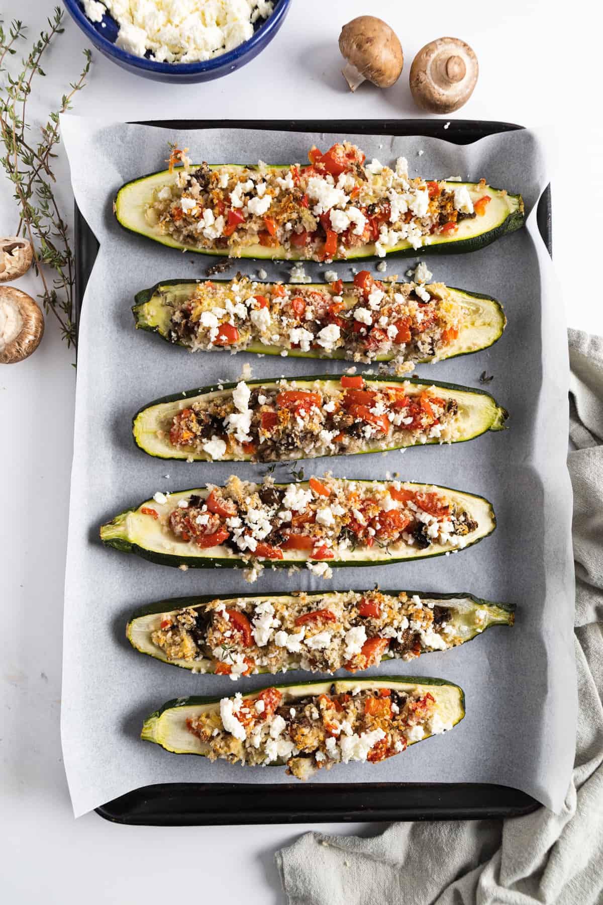 Top view of vegetarian stuffed zucchinis on a baking dish.