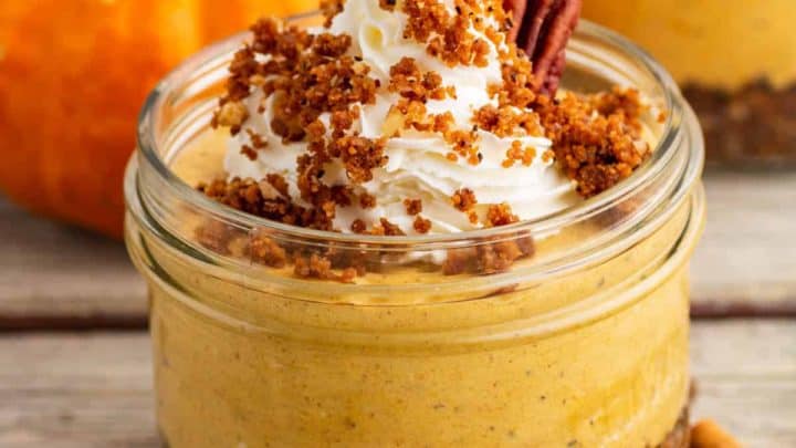 An orange pumpkin sits beside an individually sized Pumpkin Delight dessert topped with gingersnap crumbs and pecans.